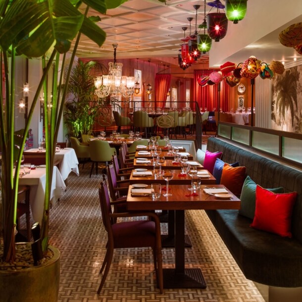 Farbenfroh eingerichteter Speisesaal eines modernen Restaurants mit Palmendekor.