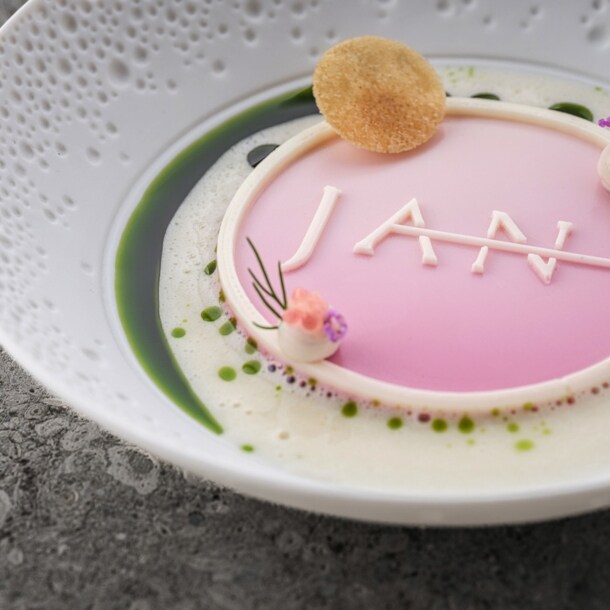 Eine kunstvoll angerichtete Speise in Pastelltönen mit dem Schriftzug JAN auf einem weißen Teller.