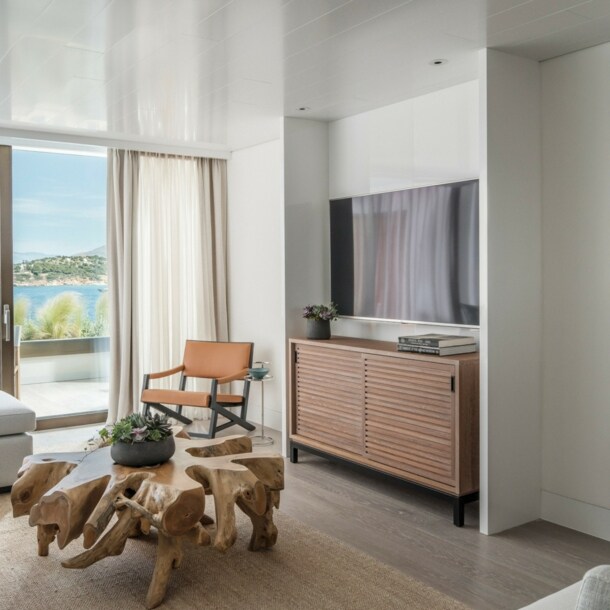 Helle Hotelsuite mit Couchtisch aus Wurzelholz und Balkon zum Meer.