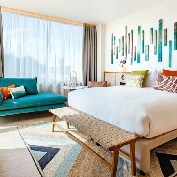 Ein helles, modernes Hotelzimmer mit Doppelbett und farbenfrohen Gestaltungselementen.