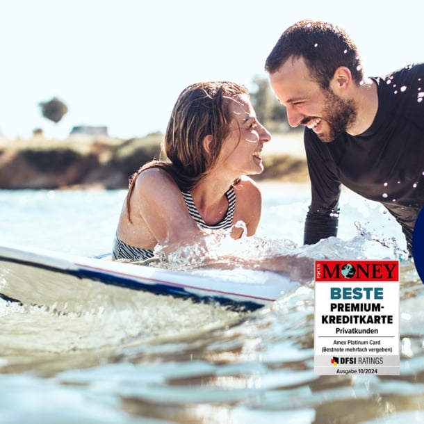 Ein lachendes Paar mit Surfboard im Meer.