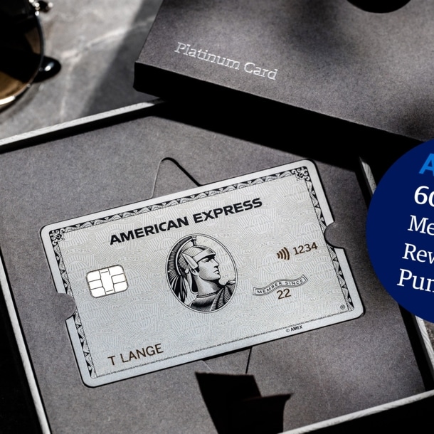 American Express Platinum Card aus Metall in einer geöffneten Präsentationsbox aus grauer Feinkartonage auf einem Marmortisch.