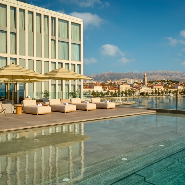 Großer Außenpool mit Liegestühlen auf der Terrasse des Hotel Ambasador in Split.