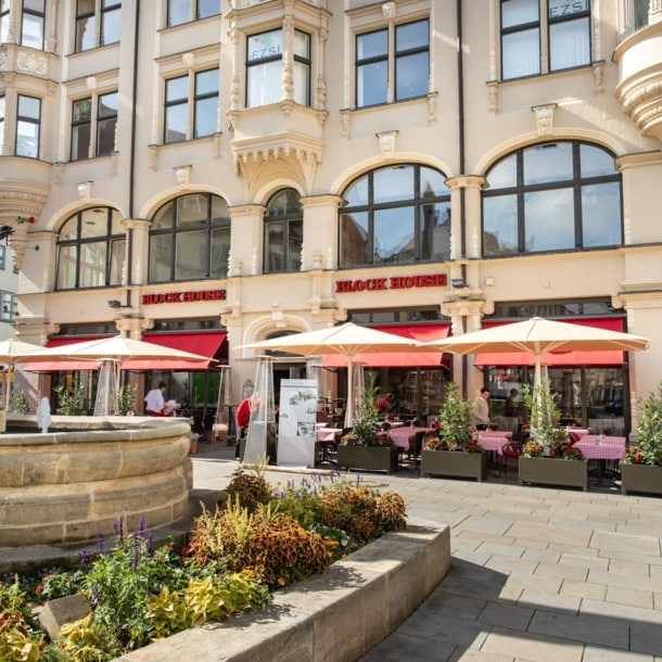 Block House Restaurant mit Außengastronomie in einem historischen Gebäude an einem Platz mit Brunnen in einer Altstadt.