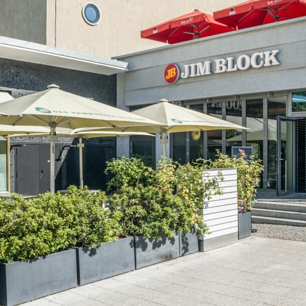 Eingang zu einem Jim Block Restaurant in einem grauen Gebäude.