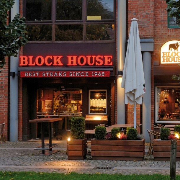 Eingangsbereich eines Block House Restaurants in einem Rotklinkerhaus mit Leuchtreklame.