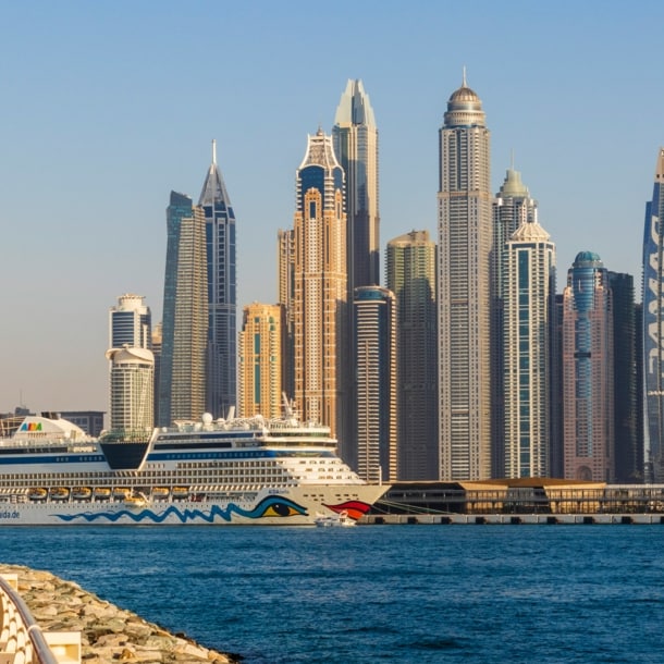 Ein AIDA Kreuzfahrtschiff vor der Skyline Dubais.