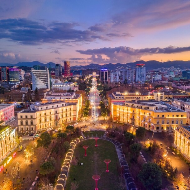 Beleuchtetes Stadtpanorama von Tirana bei Abenddämmerung aus der Luftperspektive.