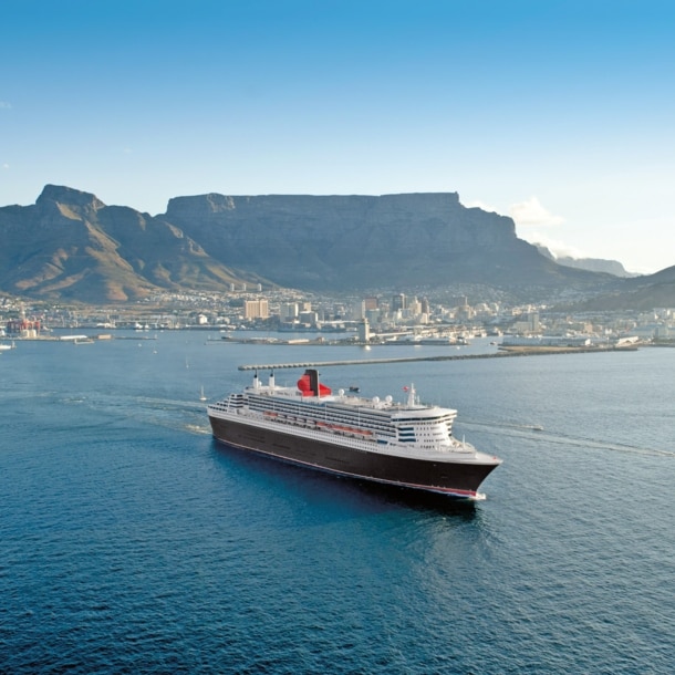 Kreuzfahrtschiff Queen Mary 2 im Wasser vor der Skyline Kapstadts.