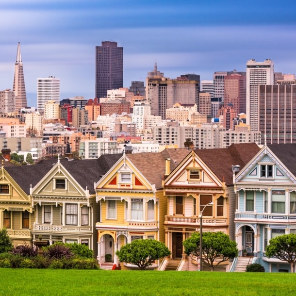 Skyline von San Francisco mit viktorianischen Holzhäusern vor Hochhäusern im Hintergrund.