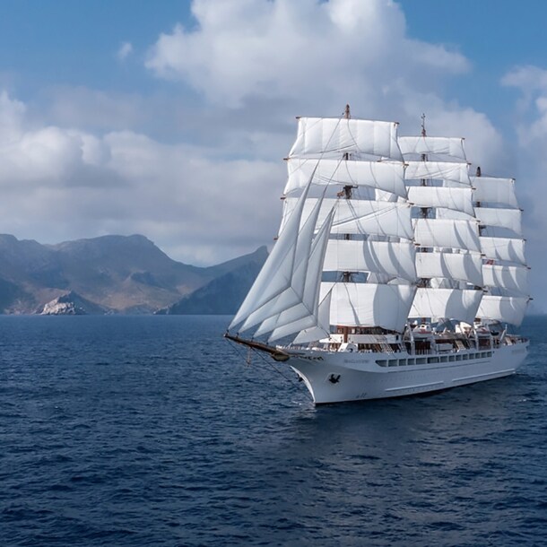 Großes Segelschiff auf dem Meer, im Hintergrund Berge