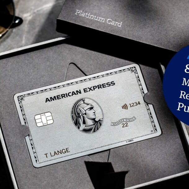 American Express Platinum Card aus Metall in einer geöffneten Präsentationsbox aus grauer Feinkartonage auf einem Marmortisch.