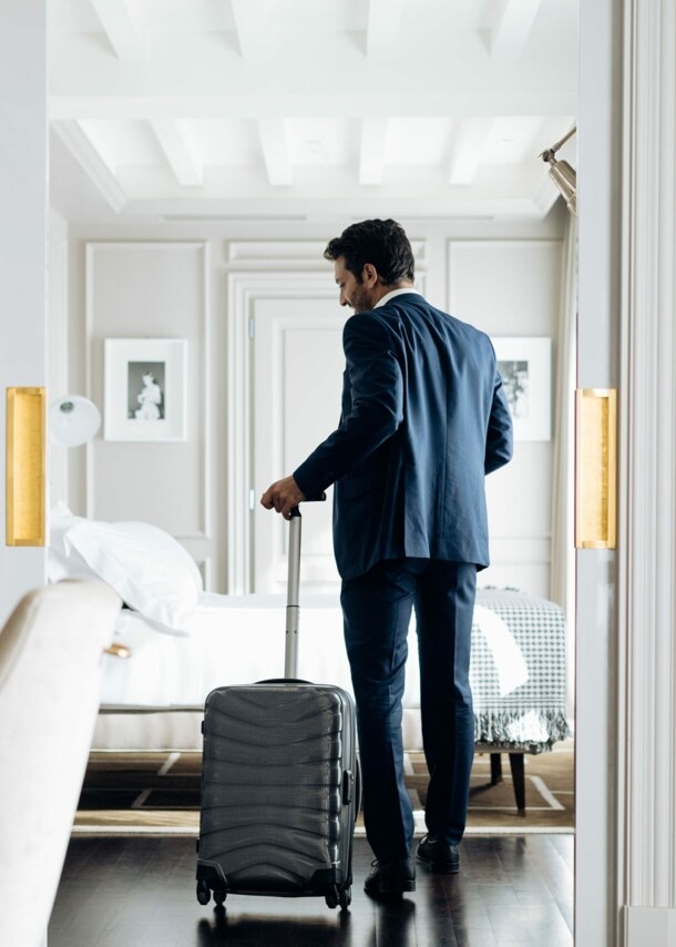 Ein junger Geschäftsmann mit Rollkoffer in einer hellen, luxuriösen Hotelsuite