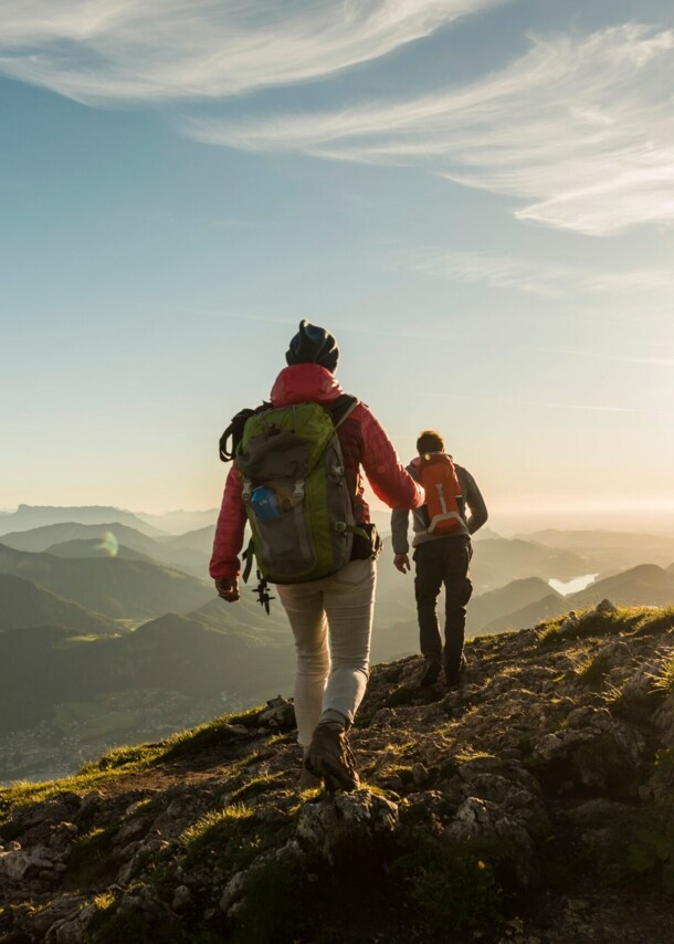 Zwei Personen wandern auf einem Berg mit beeindruckendem Panorama.