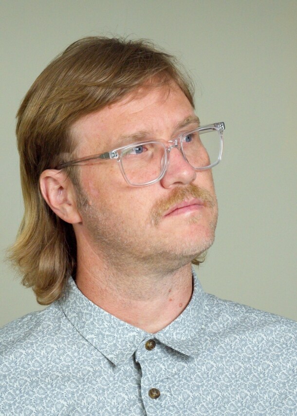 Ein Mann mit einem Mullet-Haarschnitt und Brille