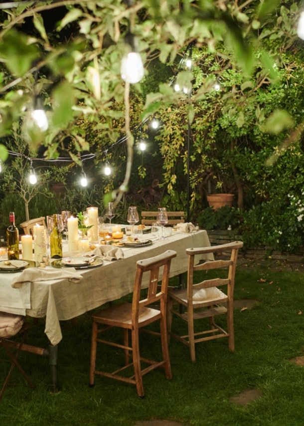 Ein gedeckter Tisch in einem Garten mit stimmungsvoller Beleuchtung bei Nacht