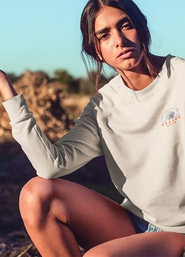 Eine junge Frau posiert in einem hellen Sweatshirt in der Natur