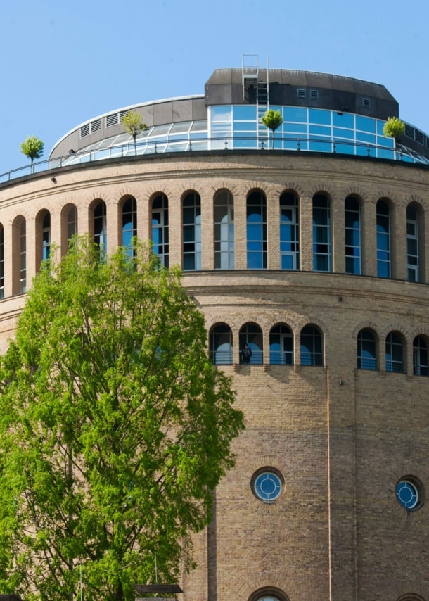 Ein runder, historischer Wasserturm mit moderner Terrasse