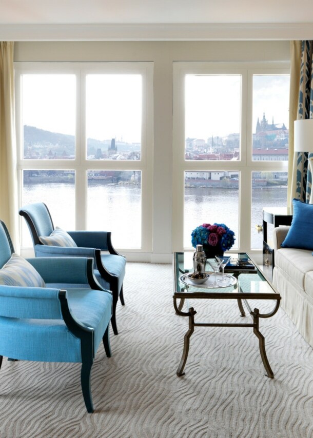 Hotelsuite am Wasser mit Panoramablick auf die Prager Skyline durch bodentiefe Fenster.