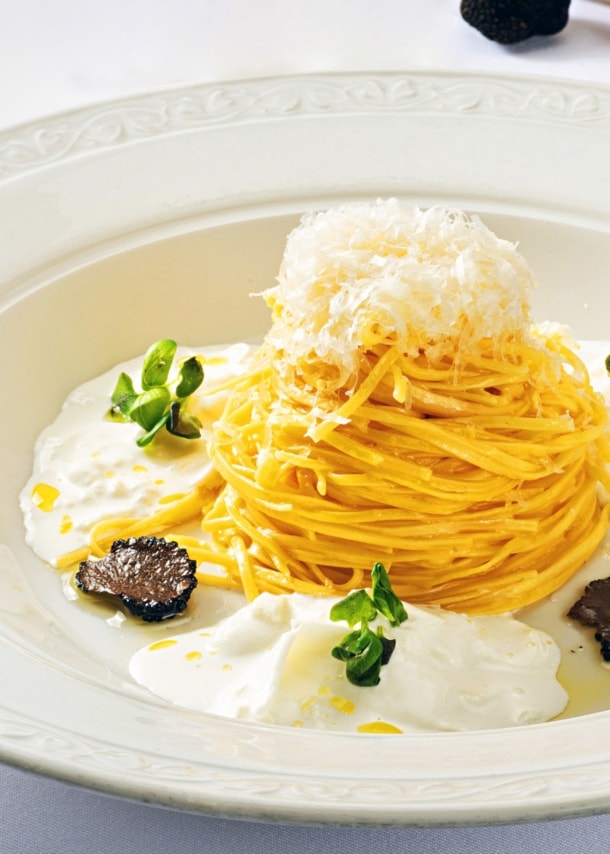 Spaghetti-Gericht mit Burrata und Trüffel, edel angerichtet auf einem weißen Teller.