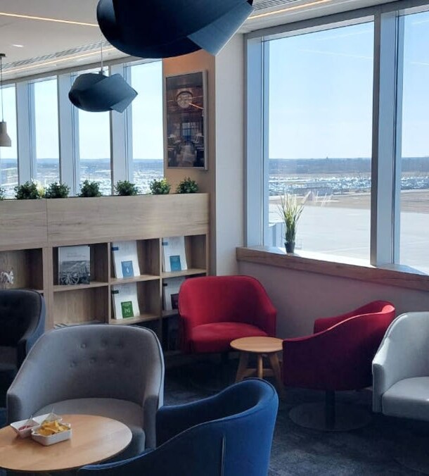 Flughafen-Lounge mit Sitzgruppen und Blick aufs Rollfeld.