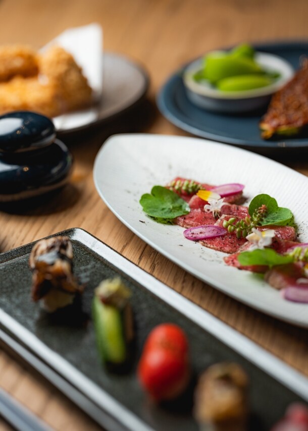 Gedeckter Holztisch mit japanischen Tapas und Sushi-Kreationen.