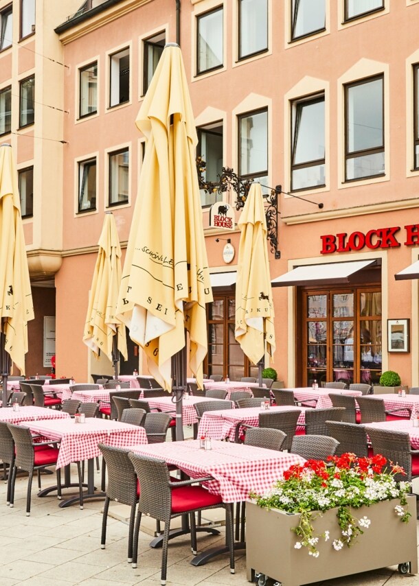 Block House Restaurant mit Außengastronomie auf einem Platz in einer Altstadt.