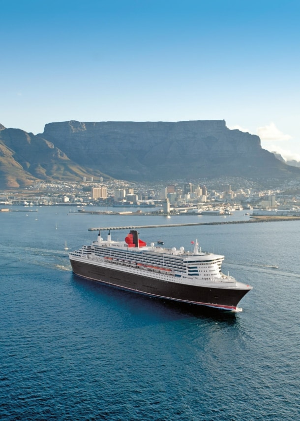 Kreuzfahrtschiff Queen Mary 2 im Wasser vor der Skyline Kapstadts.