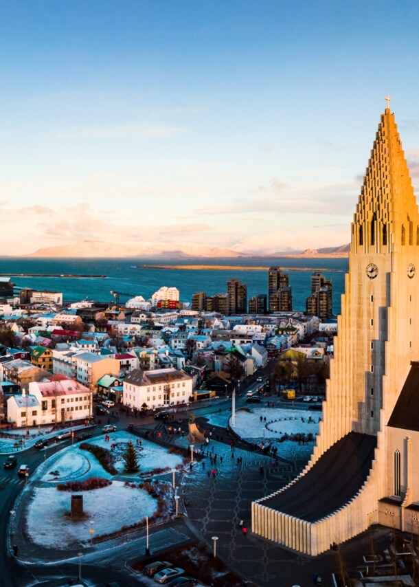 Skyline von Reykjavik mit Pfarrkirche vor Meerespanorama mit schneebedeckten Bergen.