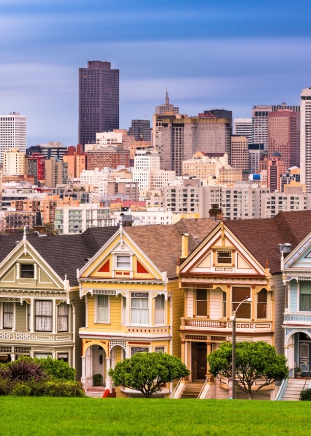 Skyline von San Francisco mit viktorianischen Holzhäusern vor Hochhäusern im Hintergrund.