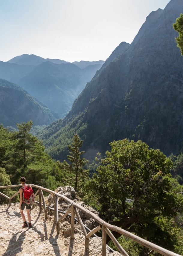 Eine Person beim Wandern in der Samaria-Schlucht auf Kreta, im Hintergrund Vegetation und Berggipfel.