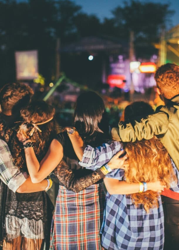 Jubelnde Zuschauer von hinten vor einer Bühne auf einem Musikfestival bei Nacht. 