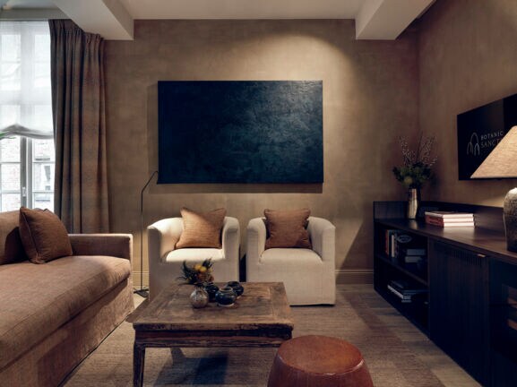 Luxuriöse Hotelsuite mit Designermöbeln in Natur- und Brauntönen und einem Fernseher.