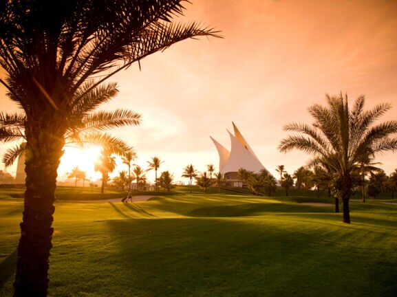 Ein gepflegter Golfplatz mit Palmen im Abendlicht
