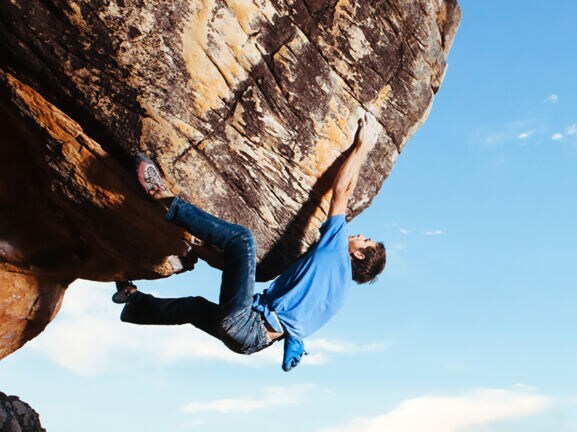 Eine Person hängt an einer Felswand ohne Sicherung