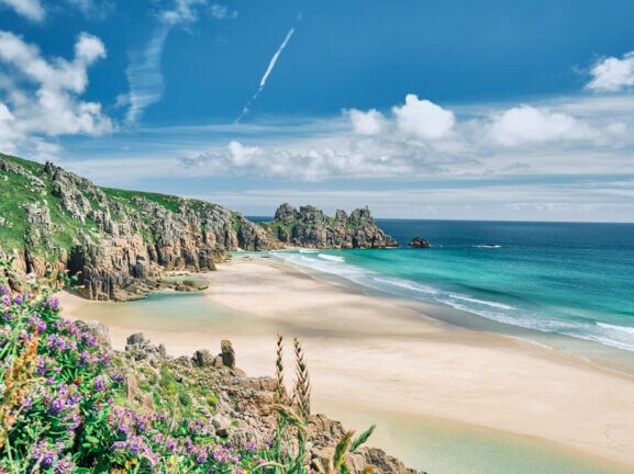 Blick auf die Küste von Cornwall mit Sandstrand, kristallblauem Wasser und Felsvorsprüngen