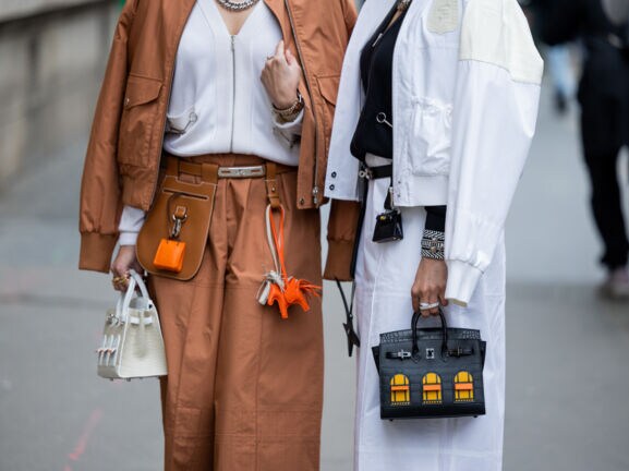 Bildausschnitt der Körpermitte von zwei Frauen, die Handtaschen tragen