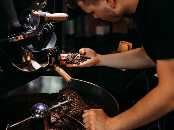 Ein Mann kontrolliert die Röstung von Kaffeebohnen