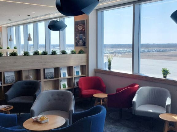 Flughafen-Lounge mit Sitzgruppen und Blick aufs Rollfeld.