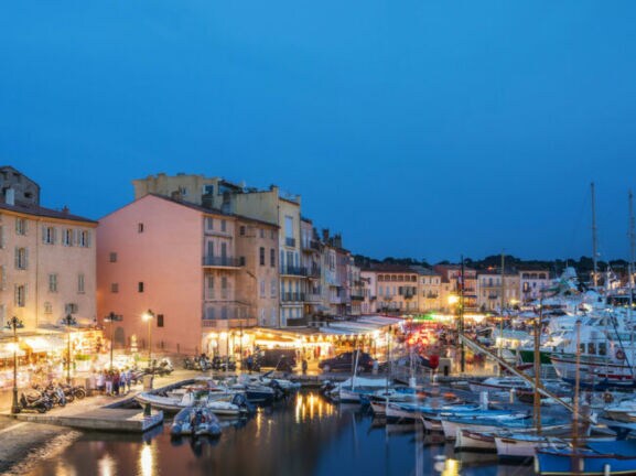 Beleuchtete Restaurants am Hafen von Saint Tropez am Abend.