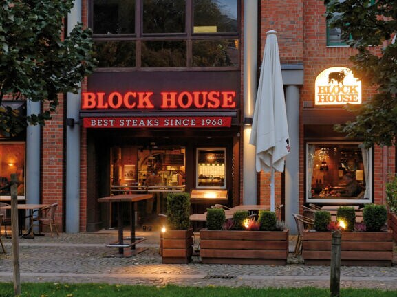 Eingangsbereich eines Block House Restaurants in einem Rotklinkerhaus mit Leuchtreklame.