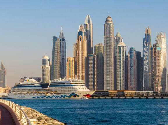 Ein AIDA Kreuzfahrtschiff vor der Skyline Dubais.