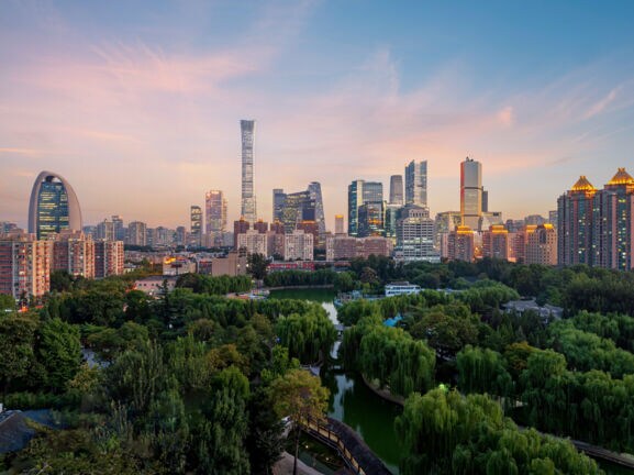 Erleuchtete Skyline von Peking mit Parkanlage in der Dämmerung.