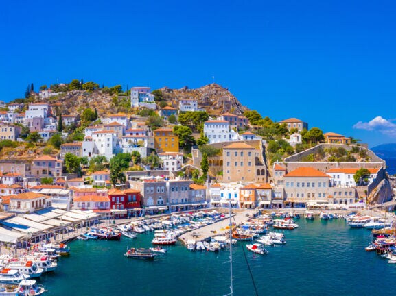 Mediterrane Ortschaft in Hanglage am Meer mit Hafenpromenade und Fischerbooten.