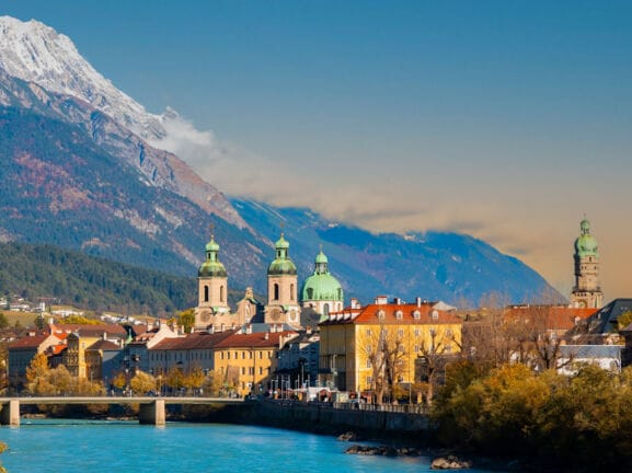 Skyline der Innsbrucker Altstadt am Fluss vor Bergpanorama.