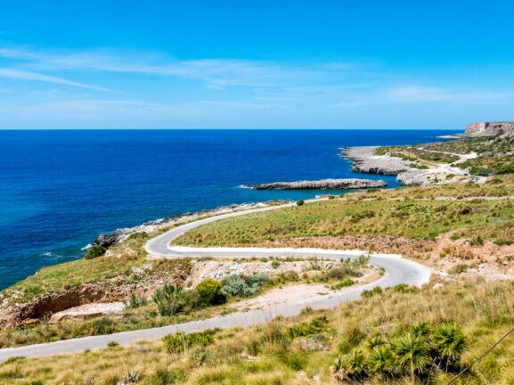 Kurvige Küstenstraße in mediterraner Landschaft.