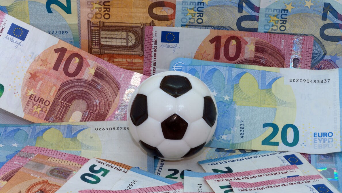 Ein Fußball vor einem Hintergrund aus Geldscheinen