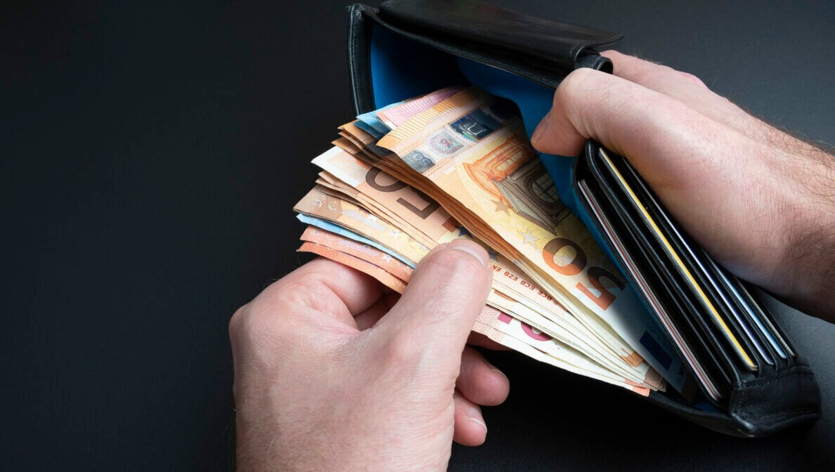 Hände nehmen Geldscheine aus einer Geldbörse