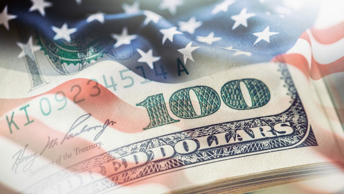 Eine Bildkomposition aus einer US-Dollar-Note und der US-amerikanischen Flagge.