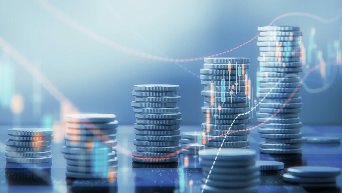 CGI-Darstellung von mehreren Münzstapeln, über die Aktienkursverläufe dargestellt sind.